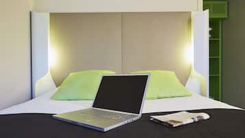 A bed with a laptop and a magazine on it.