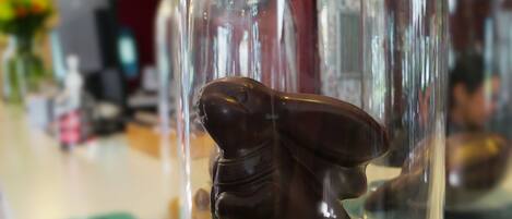 Una escultura de chocolate cubierta de chocolate bajo una cúpula de vidrio, con un fondo desenfocado de un restaurante.