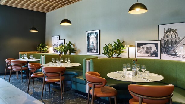 A restaurant with booths and tables, green upholstered seating, pendant lighting, and framed pictures on the walls. - Campanile PRIME - Nanterre La Défense (Nanterre)