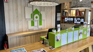 A reception desk with a green counter, a fire extinguisher, and a wall with geometric wall art.