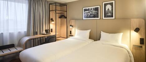 Habitación de hotel con una cama grande, un escritorio con silla, una cafetera y dos cuadros en la pared.