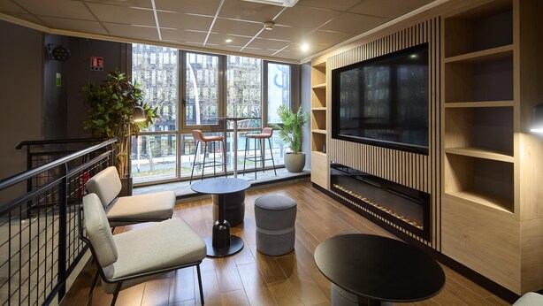 A modern interior with a large TV, seating area, and large windows. - Campanile PRIME - Arcueil (Arcueil)