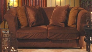 A cozy living room with a brown sofa, a wall-mounted wooden sculpture, and a potted plant. - Hotel Del Borgo (Bologna)