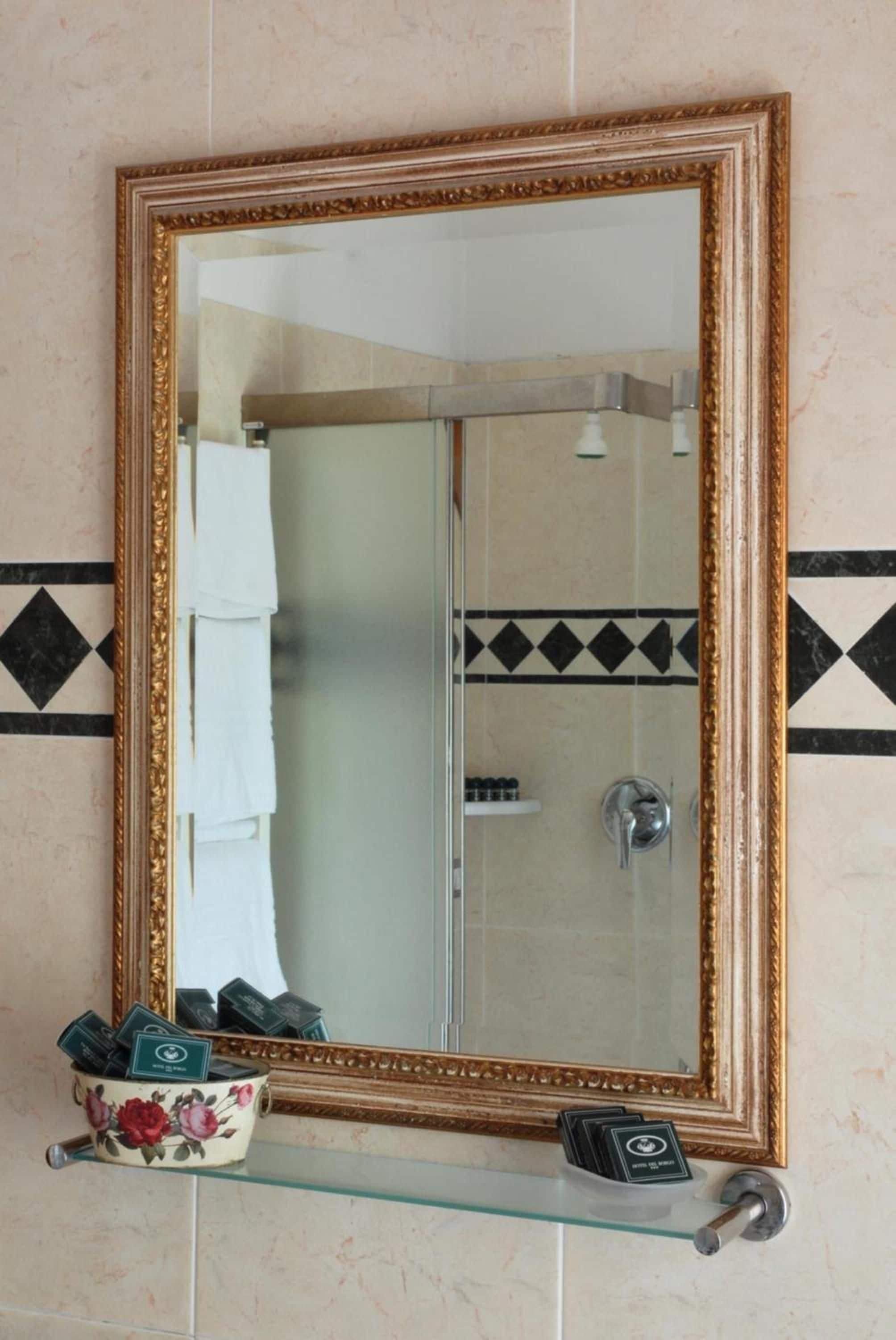 Un bagno con uno specchio grande, una doccia e un portascopevoli.