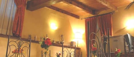 A room with a rustic wooden ceiling, a decorative wall piece, and metal-framed chairs with white cushions.
