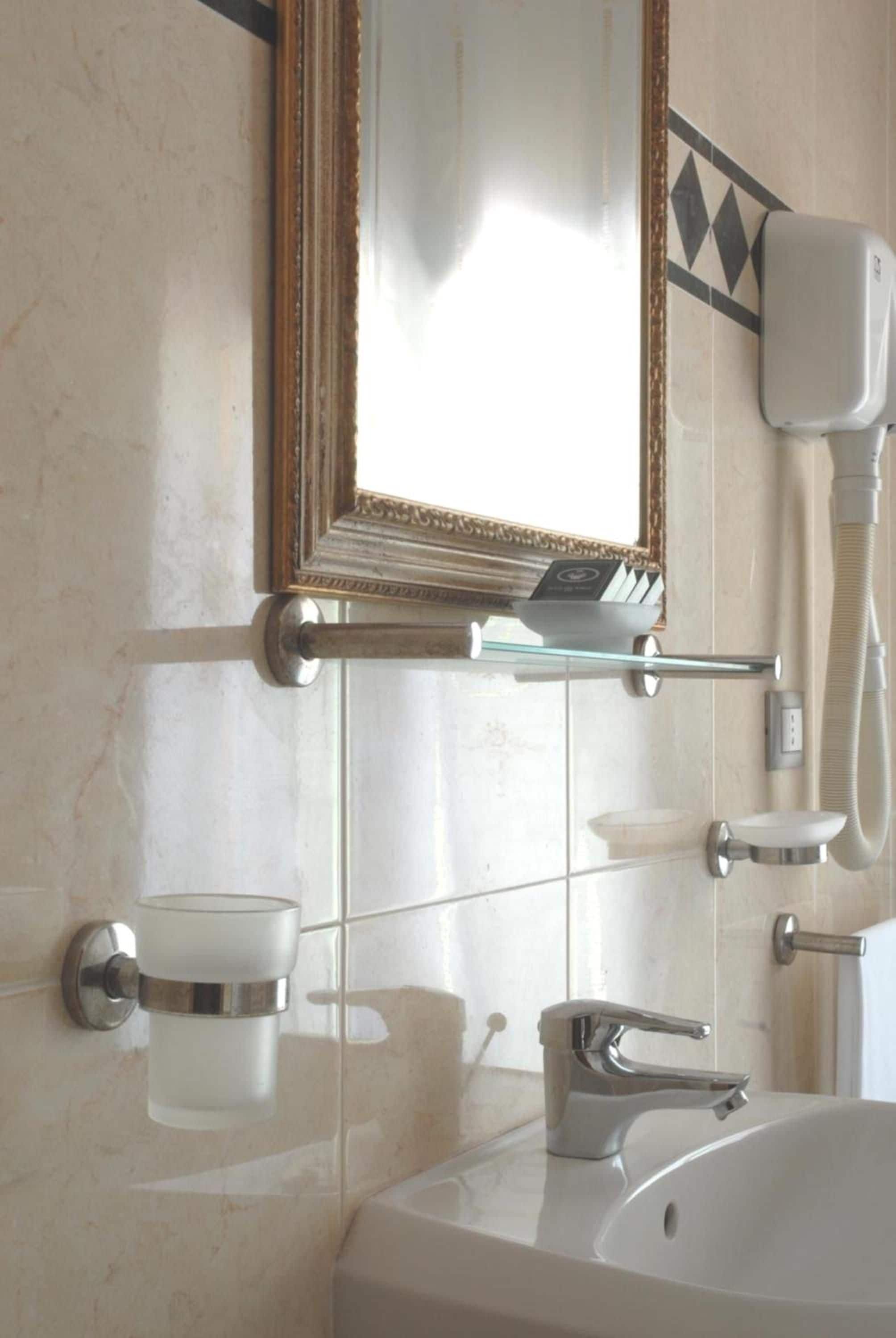 Une salle de bain équipée d’un lavabo, d’un miroir, d’un porte-serviettes et d’un sèche-cheveux.