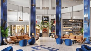 Un hall d’entrée spacieux avec des sièges bleus et bruns, un escalier central et un coin bar.