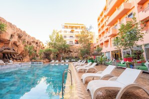 A pool area with lounge chairs and a building in the background.