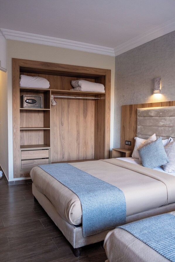 A bedroom with a large bed, a wooden wardrobe, and a nightstand.