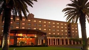 A hotel with a central courtyard, palm trees, and a well-lit entrance. - Peermont Metcourt Inn at The Grand Palm Resort (Gaborone)