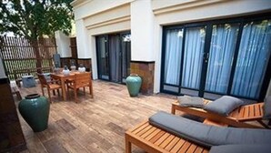 An outdoor patio with wooden furniture, including a sofa and a table. - Peermont Metcourt Inn at The Grand Palm Resort (Gaborone)