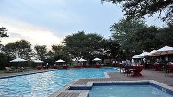 Relax by the pool surrounded by lush greenery and comfortable lounge chairs.