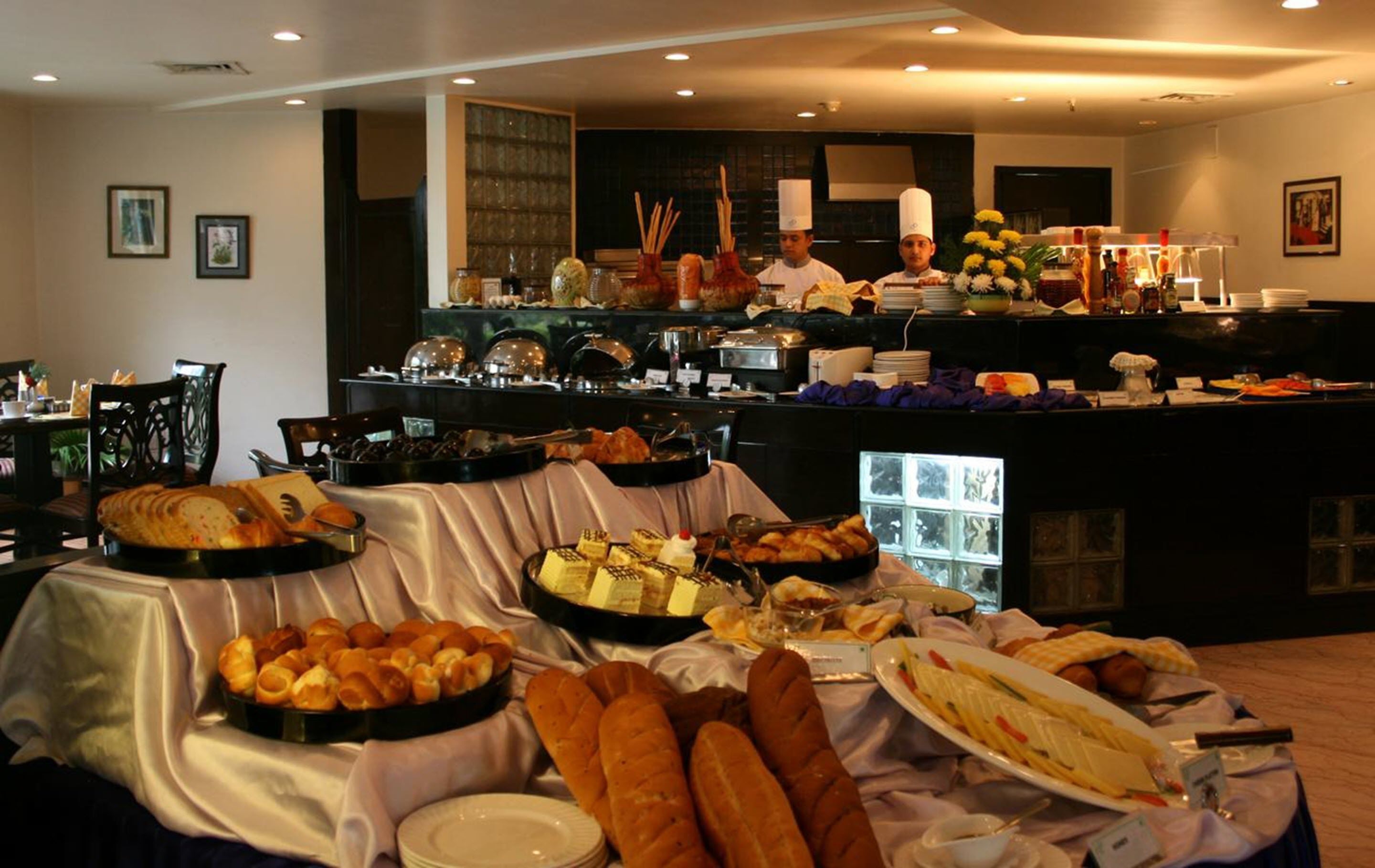 Un buffet proposant une variété de plats, avec un chef cuisinier en arrière-plan.