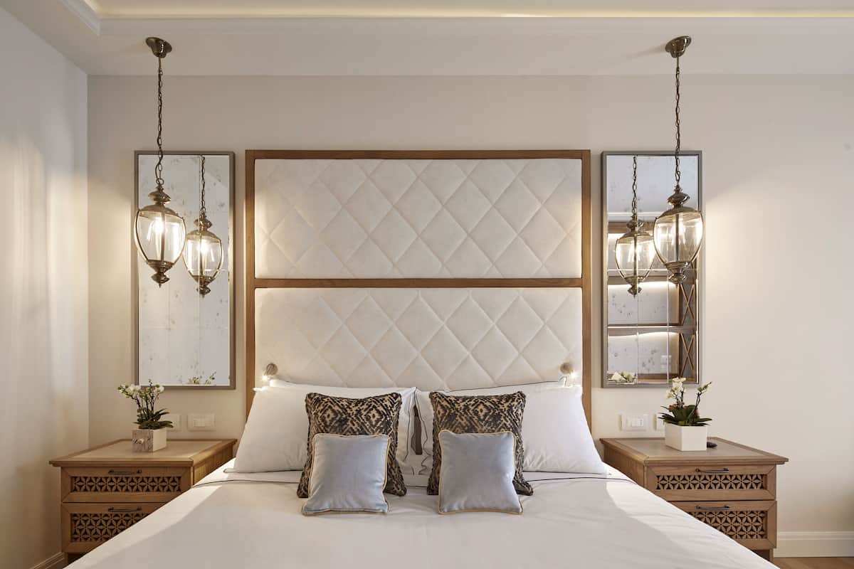 A neatly arranged bedroom with a large bed, two bedside tables, and a headboard with a quilted design.