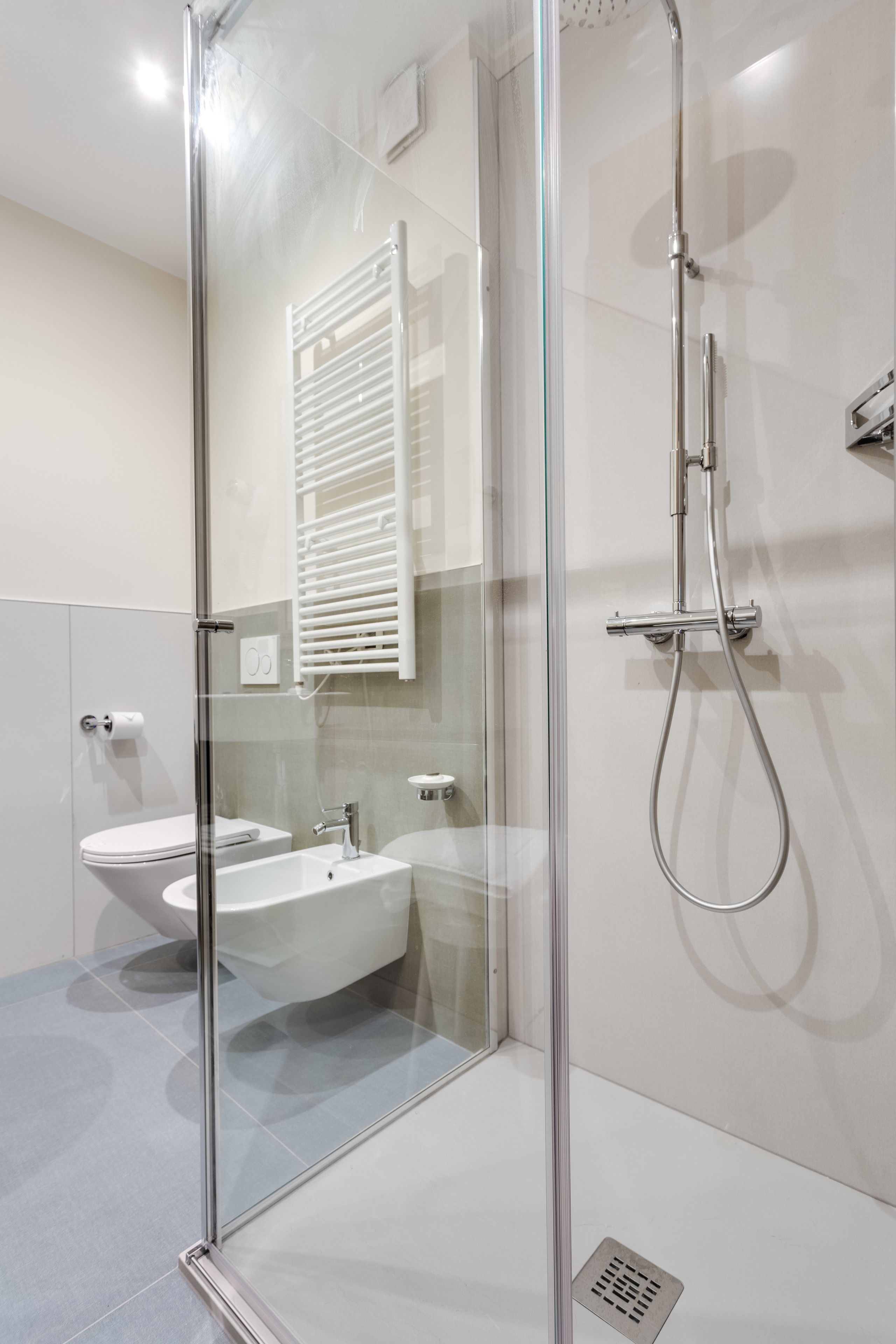 Un baño moderno con ducha envuelta en vidrio, lavamanos blanco y retrete.