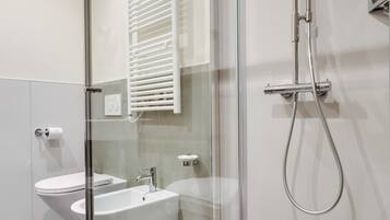 Un baño moderno con ducha envuelta en vidrio, lavamanos blanco y retrete.