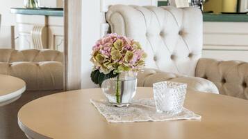 Una mesa redonda con un florero de flores y un vaso sobre un encaje.