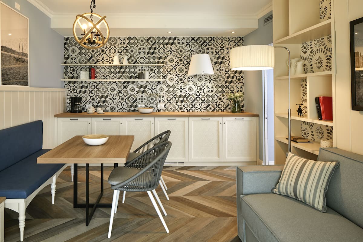 A modern kitchen with a herringbone floor pattern, a wooden dining table, and a blue sofa.