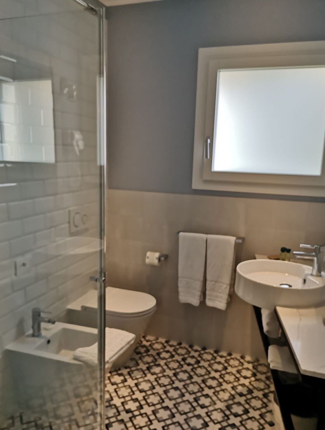 Un baño con cabina de ducha de vidrio, inodoro, lavabo y espejo.