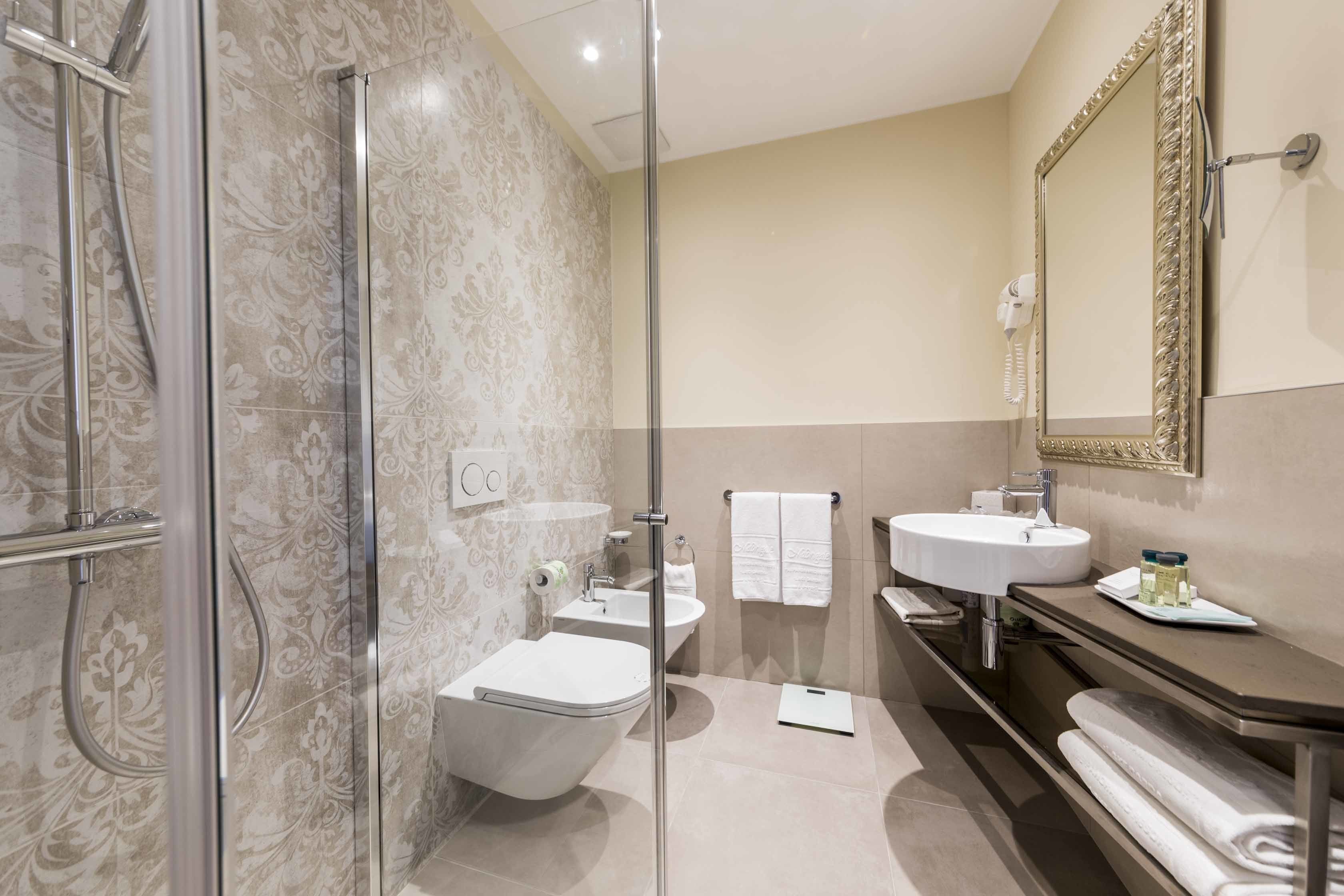 A modern bathroom with a glass-enclosed shower, two sinks, a toilet, and a large mirror.