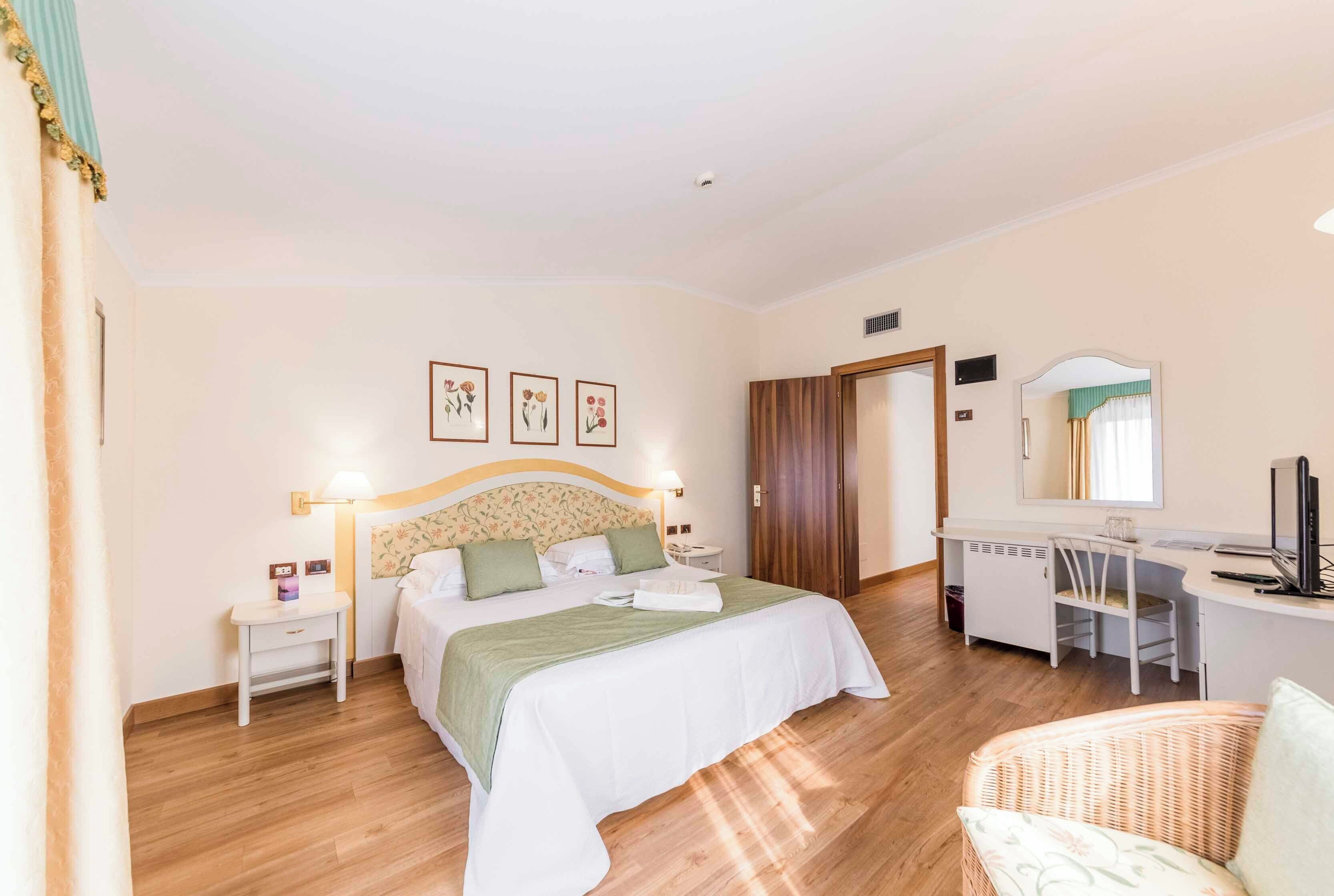 Ein Schlafzimmer mit Bett, Nachttisch, Schreibtisch, Stuhl und Spiegel.