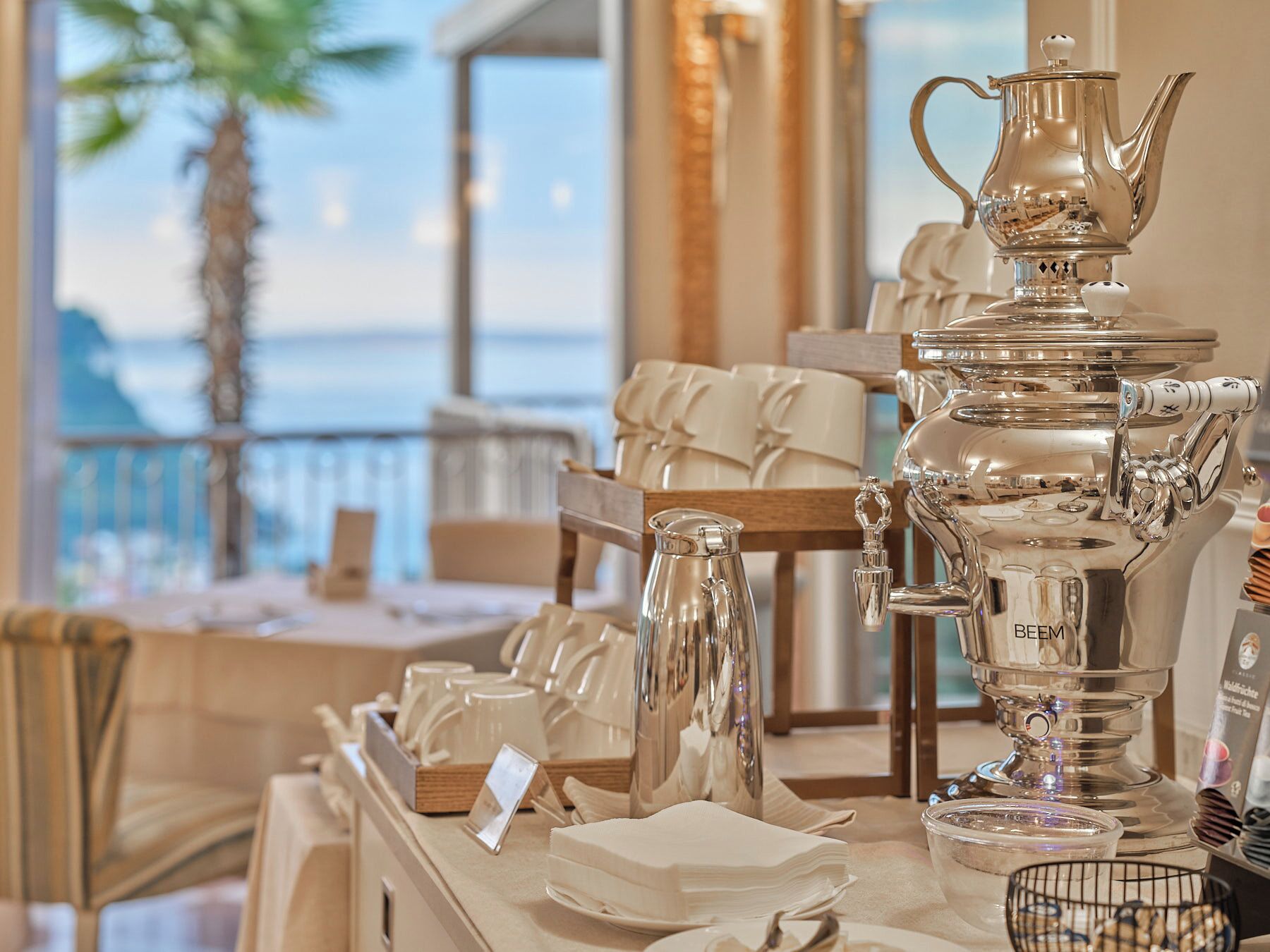 A table with a silver teapot, a coffee pot, and various cups and saucers.