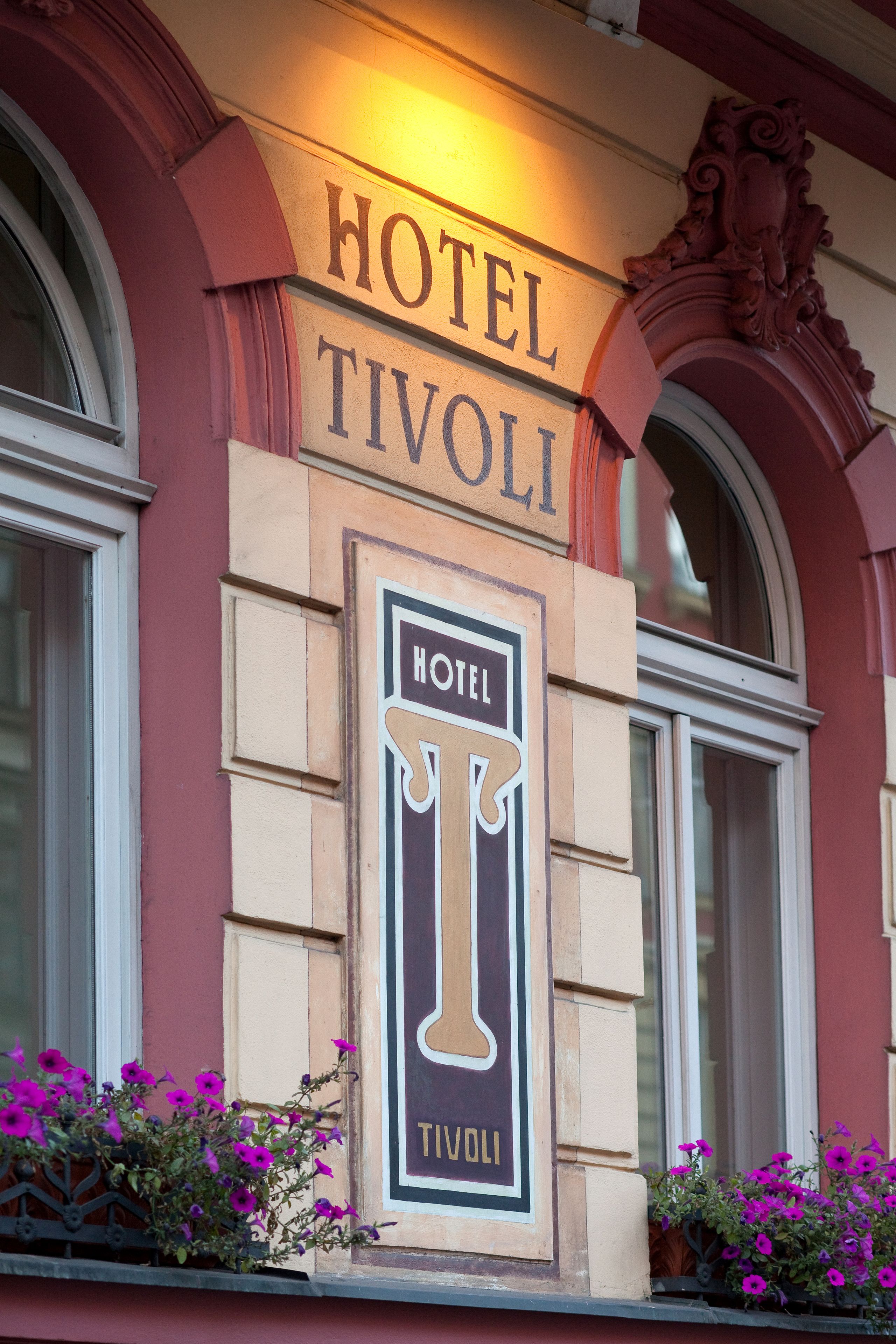 Un letrero de hotel con el nombre 'HOTEL TIVOLI' y un logotipo que muestra una 'T' y una 'V' estilizadas.