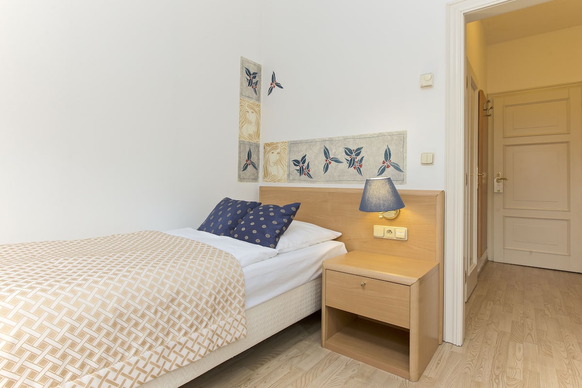 Une chambre à coucher avec un lit, une table de chevet, une lampe et des œuvres d’art murales.