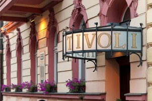 Een hotelschild met de naam 'TIVOLI' in gouden letters op een zwarte metalen lijst.