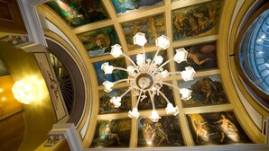 Un salón majestuoso con una gran araña, pinturas ornamentales en el techo y una estructura en forma de cúpula.