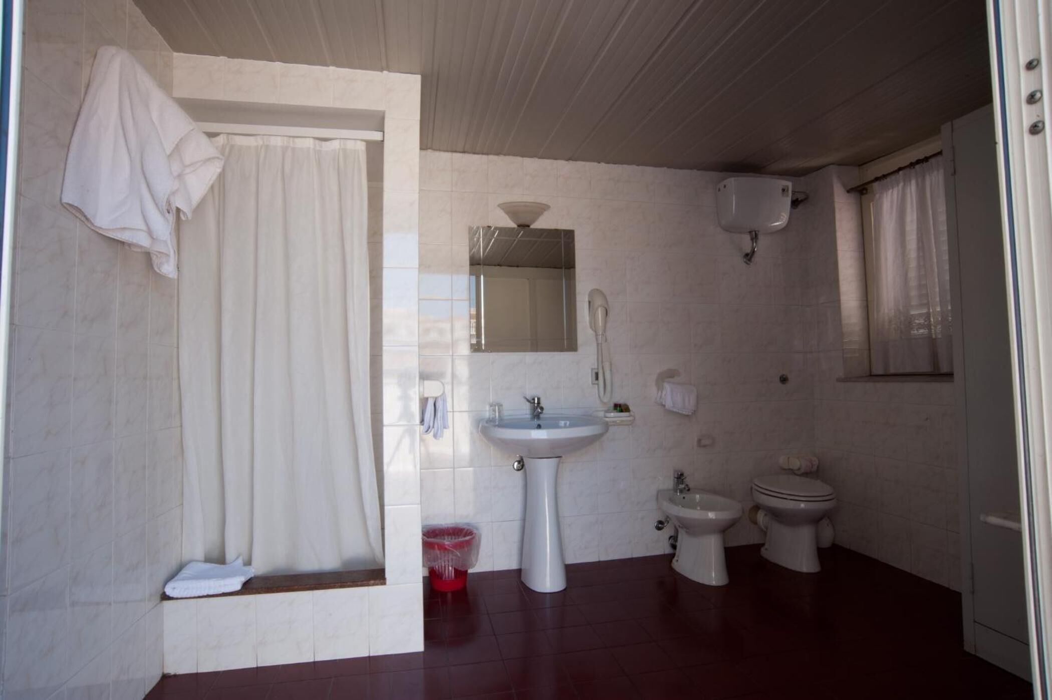 A bathroom with a sink, two toilets, a shower, and a mirror.