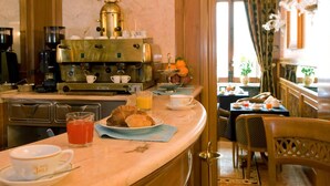 Una barra de desayuno con máquinas de café, un bol de fruta y productos para el desayuno.