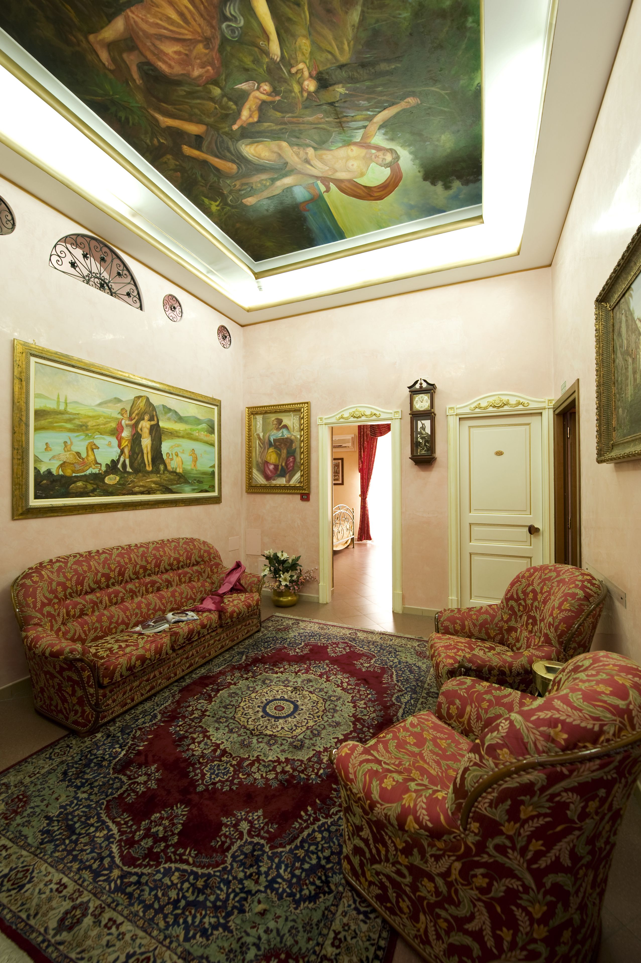 A room with a large painting on the wall, a sofa, a patterned rug, and a door.