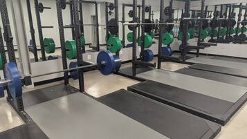 A gym with weightlifting equipment and black and grey mats.