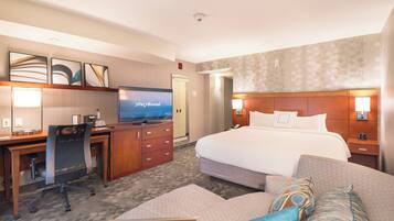 A hotel room with a bed, a desk with a computer, a television, and a sofa.
