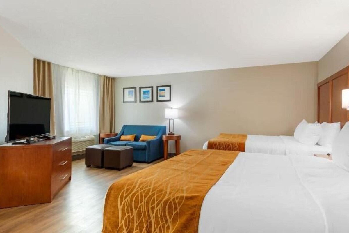 A hotel room with a bed, a TV, a sofa, and a desk.