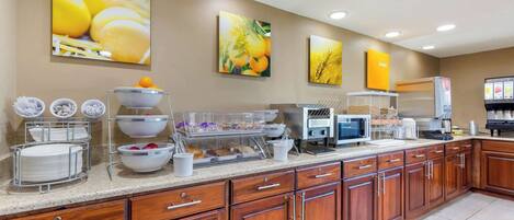 A kitchen with wooden cabinets, a countertop with various appliances, and wall-mounted artwork.