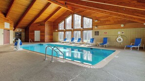 An indoor swimming pool with a wooden ceiling and large windows.