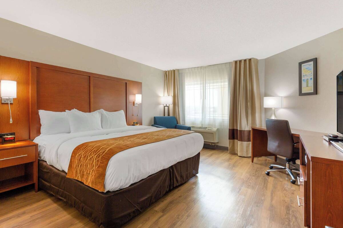 Una habitación de hotel con una cama grande, mesitas de noche, un escritorio y una silla.
