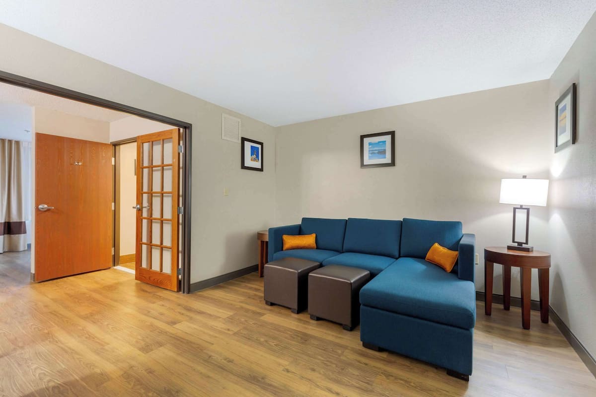 Una sala de estar con un sofá azul, dos otomanas, una puerta de madera y una lámpara.