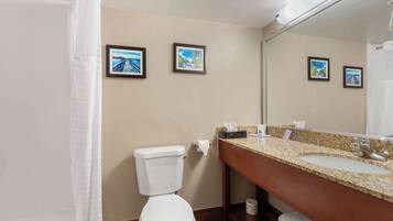 A bathroom with a toilet, sink, and two framed pictures on the wall.