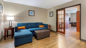 A living room with a sectional sofa, ottoman, and a lamp.