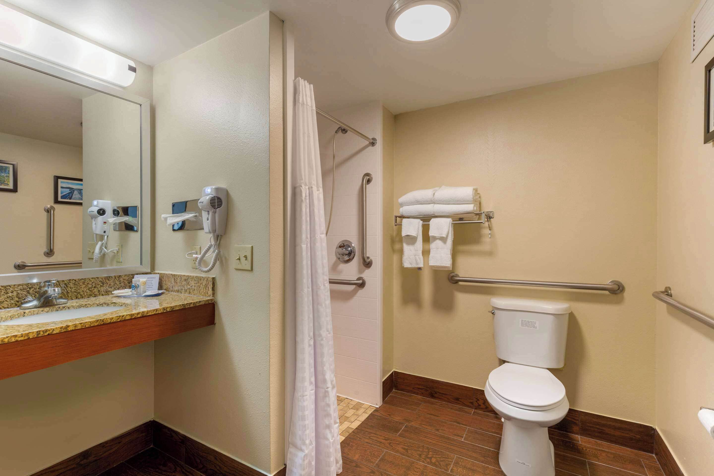 A bathroom with a sink, mirror, towel rack, shower, and toilet.