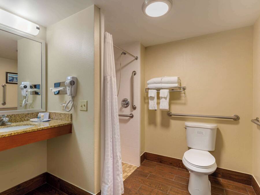 A bathroom with a sink, mirror, towel rack, shower, and toilet.