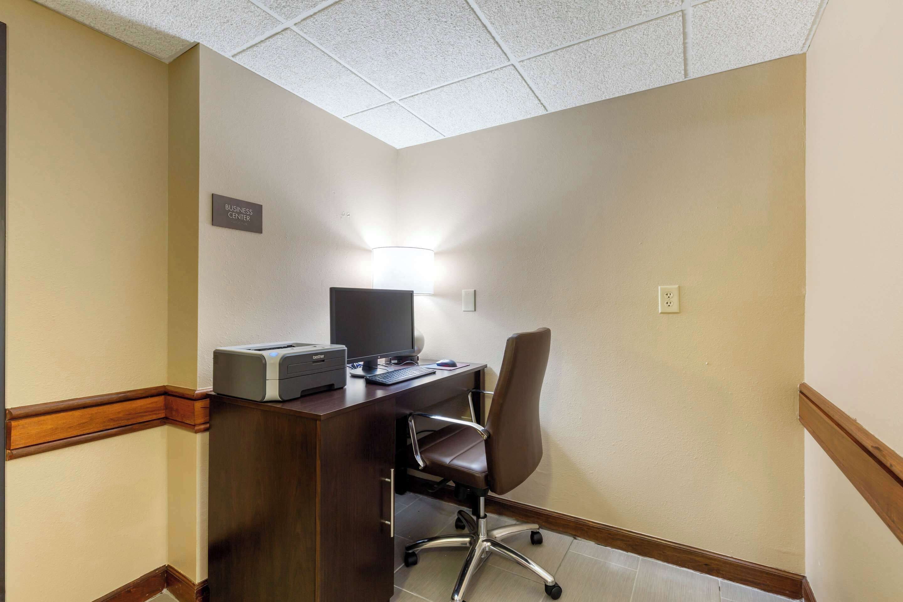 A business center with a desk, computer, and office chair.