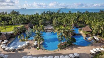 A resort with multiple swimming pools surrounded by palm trees and lounge areas.