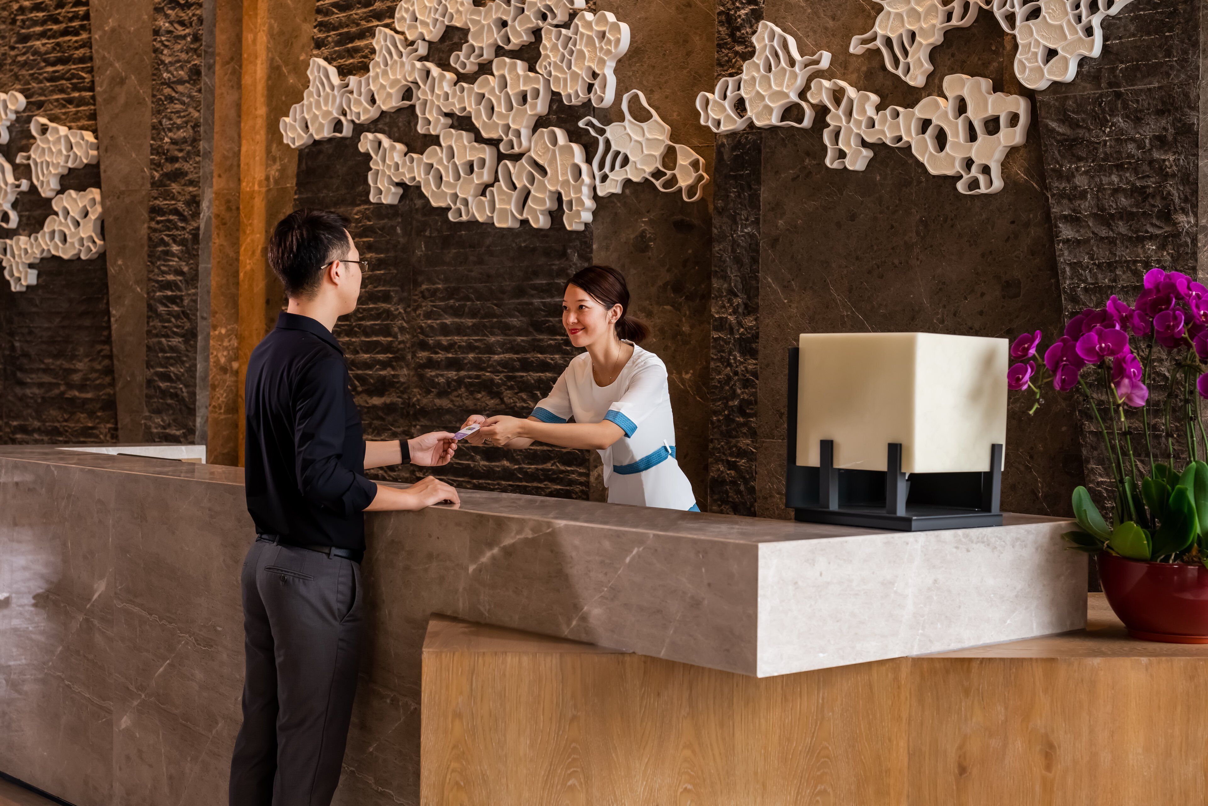 A reception area with a marble counter, a receptionist, and a customer.