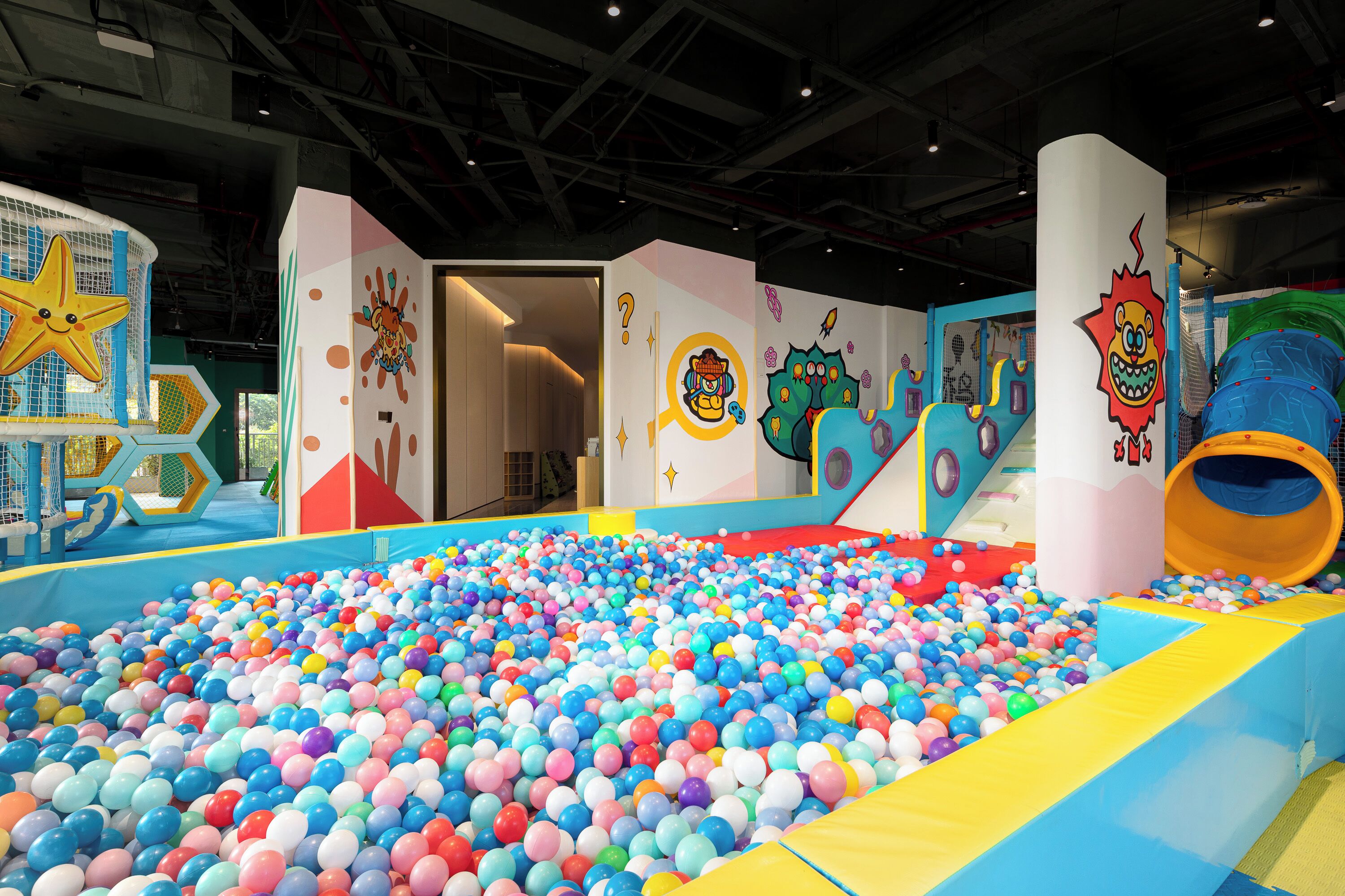 An indoor play area with a ball pit, slides, and colorful play structures.