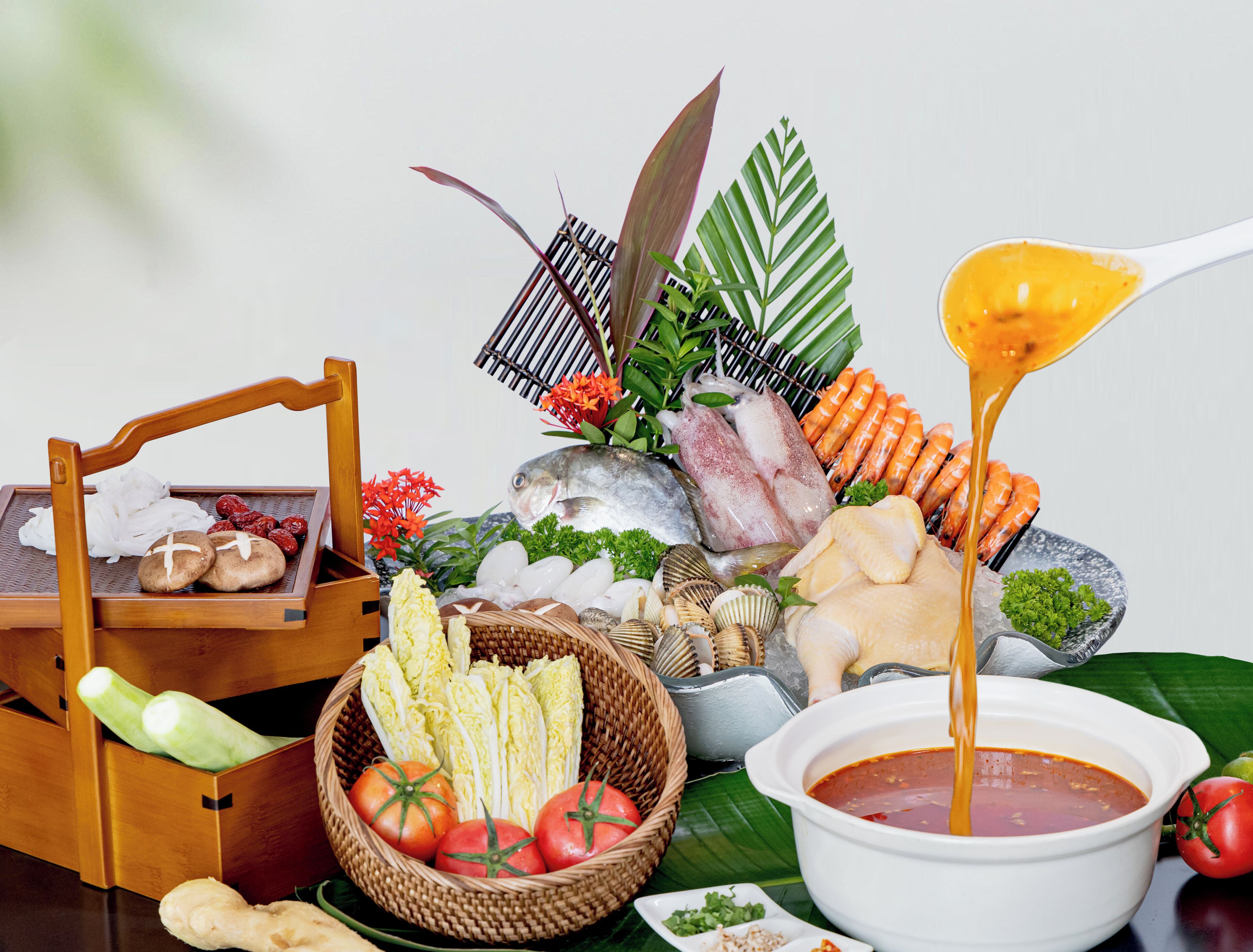 Une table sur laquelle on trouve divers aliments, notamment des fruits de mer, des légumes et un bol de soupe.