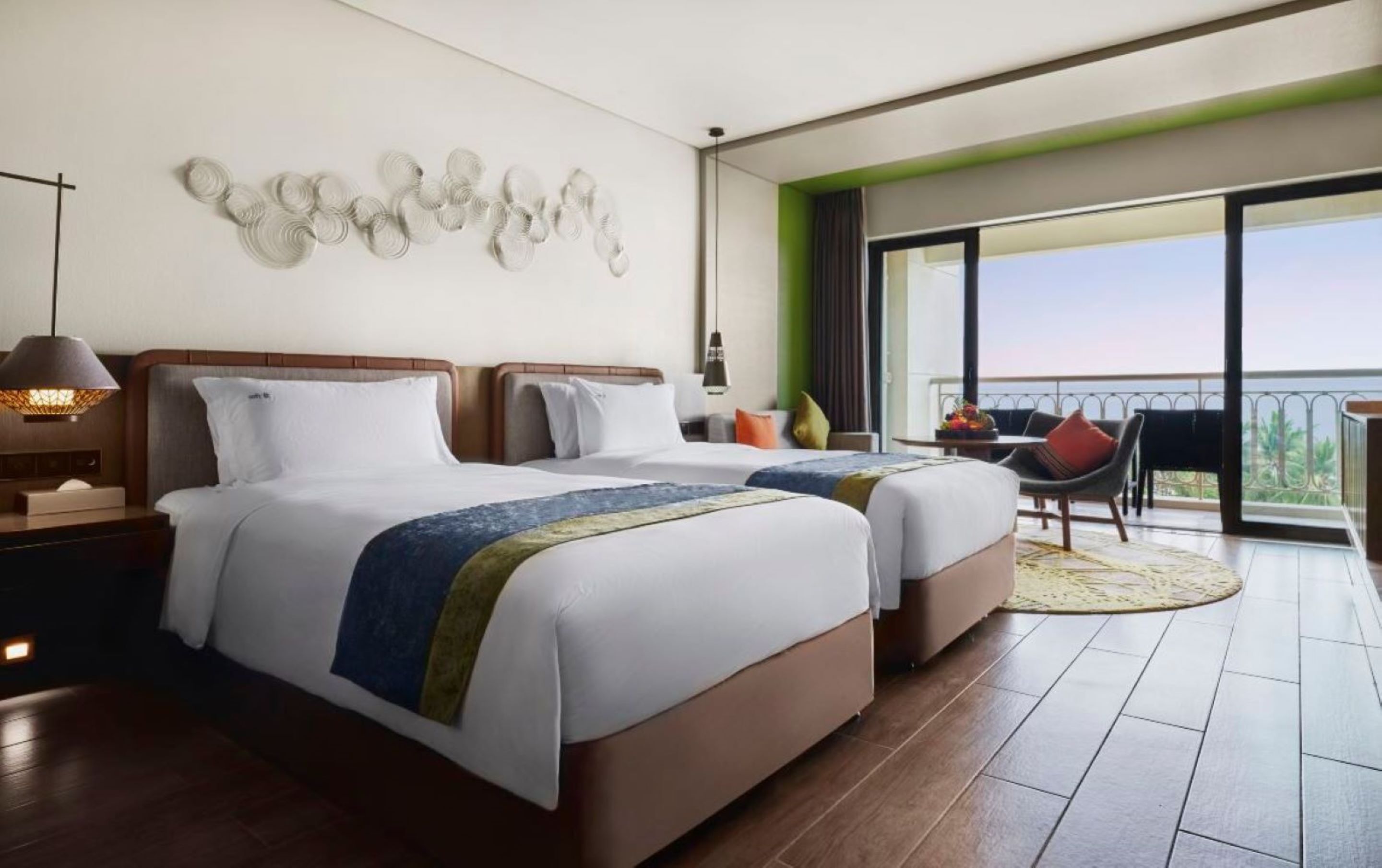 Ein Hotelzimmer mit zwei Betten, einem Balkon mit Aussicht und moderner Einrichtung.